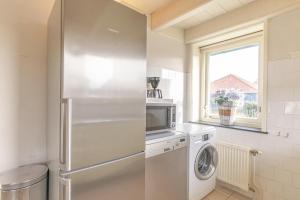 a kitchen with a refrigerator and a washer and dryer at Op t land 25 in Callantsoog +22 photos