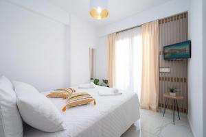 a white bedroom with a bed and a window at Amersa Luxury Apartments in Heraklio