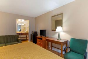 a hotel room with a bed and two chairs and a television at Rodeway Inn Colonial Heights I-95 in Colonial Heights