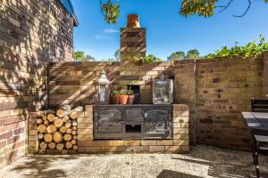 a brick wall with an outdoor fireplace in a yard at Kerrisdale Bowral in Bowral