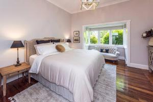 a bedroom with a large white bed and a window at Kerrisdale Bowral in Bowral