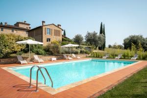 a swimming pool with chairs and umbrellas next to a house at Tenuta Di Sticciano in Certaldo