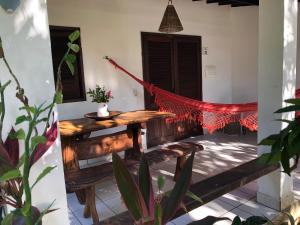 a porch with a wooden table and a hammock at Pousada das Oliveiras in Porto De Galinhas