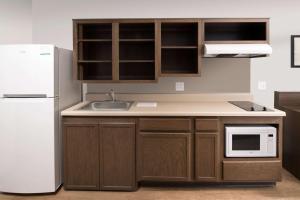 a kitchen with wooden cabinets and a white refrigerator at WoodSpring Suites Chicago Tinley Park in Tinley Park