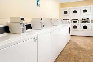 a white laundry room with white washers and dryers at WoodSpring Suites Chicago Romeoville in Romeoville