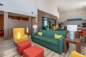 a living room with a green couch and colorful chairs at Comfort Suites Colorado Springs East - Medical Center Area in Colorado Springs