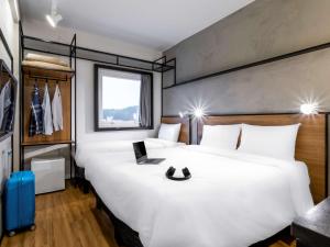 ein Hotelzimmer mit einem großen weißen Bett und einem Fenster in der Unterkunft Ibis Aruja in Arujá