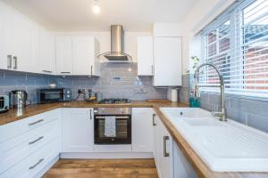 a kitchen with white cabinets and a sink at The Lake Hub in Goodmayes