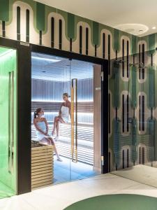 a room with glass doors with two women sitting on a bench at Falkensteiner Boutique Hotel Prague in Prague