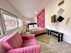 a living room with a pink couch and a bed at Apartments Aleksandra in Kragujevac