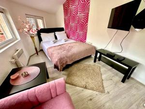 a living room with a bed and a pink couch at Apartments Aleksandra in Kragujevac