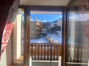 una vista da una finestra di un balcone con neve di Maison Rongier nel centro di Cogne a Cogne