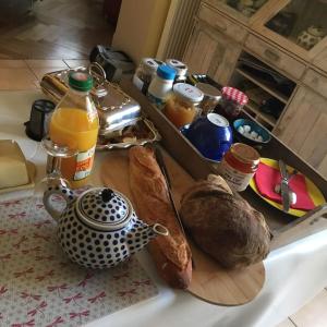 a table with bread and a teapot on a cutting board at Chambre calme indépendante avec Salle de bains -Petit déjeuner-Grande Terrasse- Proche du centre in Bordeaux