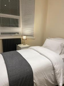 um quarto com uma cama branca e uma janela em BEAUTIFUL ROOMS ONLY FEW STEPS AWAY FROM BRUCE GROVE TOTTENHAM STADIUM em Londres