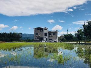 a large building with a reflection in a pond at Country Road B&B in Guangfu