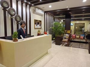 a man sitting at a reception desk in a lobby at Hotel Dr Rajkumar International in Bangalore