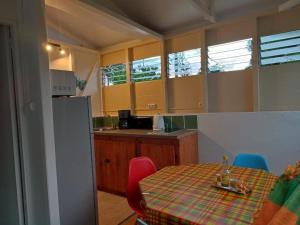 una cocina con mesa y sillas y una cocina con armarios amarillos. en Bungalow Ti Papiyon, en Bouillante