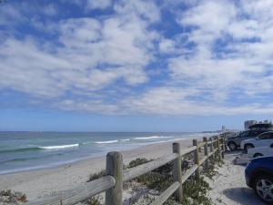 a wooden fence on the beach with cars parked at Carmel Huys in Cape Town