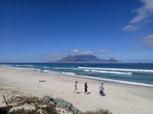 a group of people walking on the beach at Carmel Huys in Cape Town