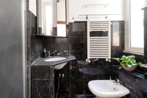 a black tiled bathroom with a sink and a mirror at Quirinale View 52 in Rome