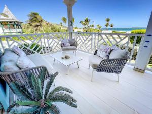 - un balcon avec deux chaises et une table basse donnant sur l'océan dans l'établissement Princess Anouk Beachfront Orient Bay Deluxe 3 BDR, à La Baie-Orientale