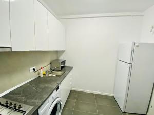 uma cozinha com armários brancos e um frigorífico branco em Plaza Residence Studio 2 em Bucareste