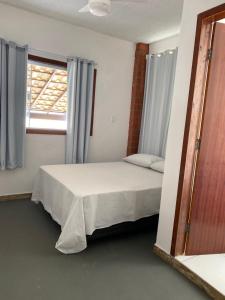 a bedroom with a bed and a window at Suites do Mar in Marataizes