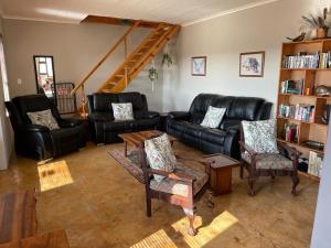 a living room with a black leather couch and chairs at Raptor's View Dullstroom in Dullstroom