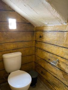 a bathroom with a toilet in a wooden wall at Suites do Mar in Marataizes