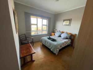 Schlafzimmer mit einem Bett, einem Tisch und einem Fenster in der Unterkunft Raptor's View Dullstroom in Dullstroom