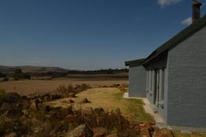 ein Haus mit Blick auf ein Feld und ein Gebäude in der Unterkunft Raptor's View Dullstroom in Dullstroom