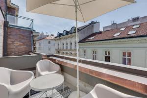 balkon z białymi krzesłami i parasolem w obiekcie Riben House Prague w Pradze