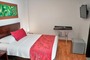 a bedroom with a bed with a red pillow and a desk at Hotel Volare in Armenia