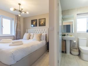 ein Schlafzimmer mit einem großen weißen Bett und einem Waschbecken in der Unterkunft Pass the Keys Stylish 2BR House in Leafy Warfield with Garden in Bracknell