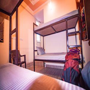 a room with two bunk beds and a chair at Triple One Hostel Tapovan Rishikesh in Rishīkesh