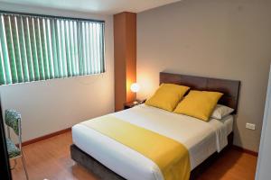 a bedroom with a bed with yellow pillows and a window at Hotel Volare in Armenia