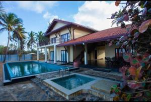 a house with a swimming pool in front of it at Reef Bungalow Hotel in Pamunugama