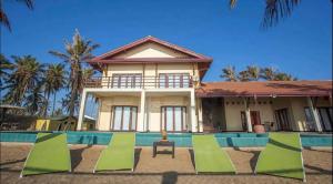 a house with a pool and chairs in front of it at Reef Bungalow Hotel in Pamunugama
