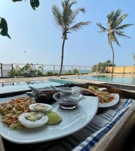 een bord eten op een tafel naast een zwembad bij Reef Bungalow Hotel in Pamunugama
