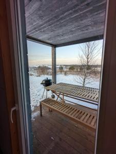 una veranda coperta con panchina e neve di Cozy house with sauna by the lake a Lokuti