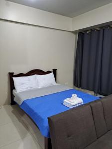 een slaapkamer met een bed met een blauwe deken en een bank bij MRMcondotel in Manilla
