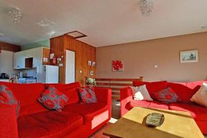 St Ann's 21 في Gunnislake: غرفة معيشة مع أريكة حمراء وطاولة