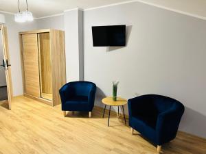 a living room with two blue chairs and a table at Apartamenty Route 65 in Grabówka