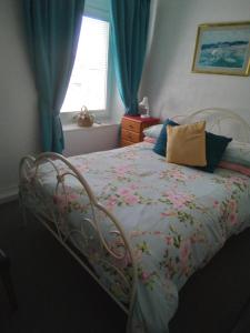 um quarto com uma cama com um cobertor floral e uma janela em Applebys Guest House em Holyhead