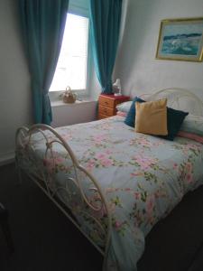 a bedroom with a bed with a floral blanket and a window at Applebys Guest House in Holyhead