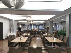 a dining room with tables and chairs and chandeliers at Seehotel Losheim in Losheim