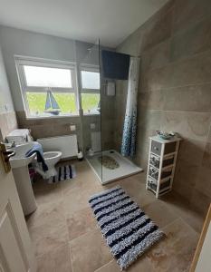 a bathroom with a shower and a sink and a mirror at Rosie's Cottage in Moville