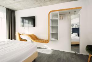 ein Schlafzimmer mit einem Spiegel, einem Schreibtisch und einem Stuhl in der Unterkunft Tailormade Hotel IDEA Spreitenbach in Spreitenbach