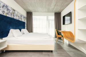 una camera con letto bianco e scrivania di Tailormade Hotel IDEA Spreitenbach a Spreitenbach