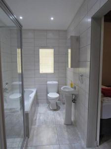 a bathroom with a toilet and a tub and a sink at Lions Rest on Vaal River in Vanderbijlpark